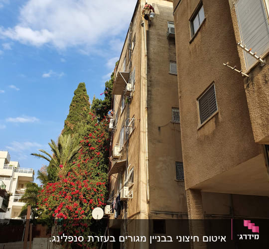 עובד בגובה על בניין עם ציוד בטיחות